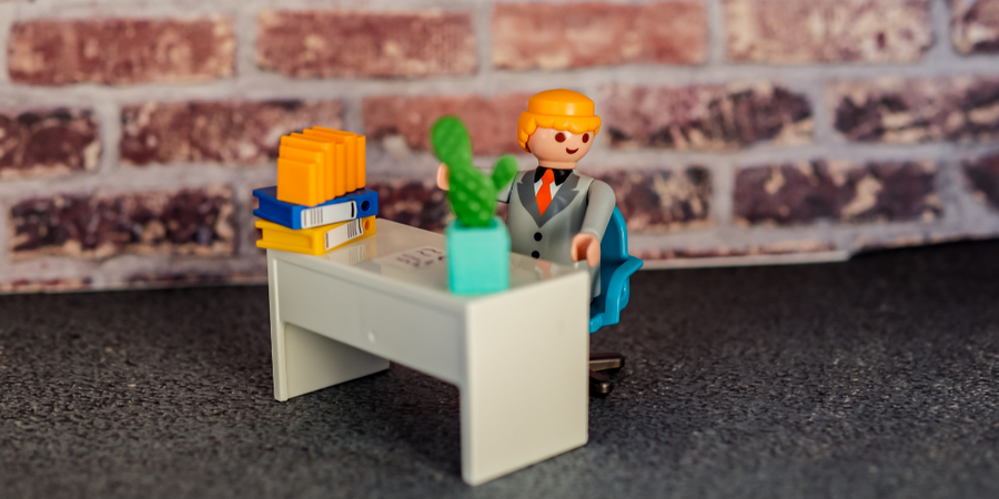 23- Eine Playmobilfigur sitzt an seinem Arbeitsplatz.