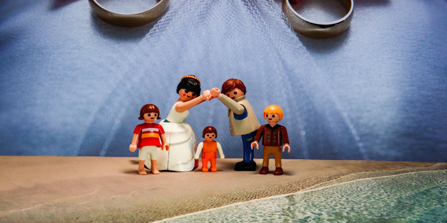 16- Zwei heterosexuelle Playmobilfiguren heiraten, ihre drei Kinder stehen neben ihnen.