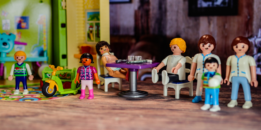 25- Eine Gruppe von Playmobilfiguren sitzt um einen Tisch in einem Bistro und essen.